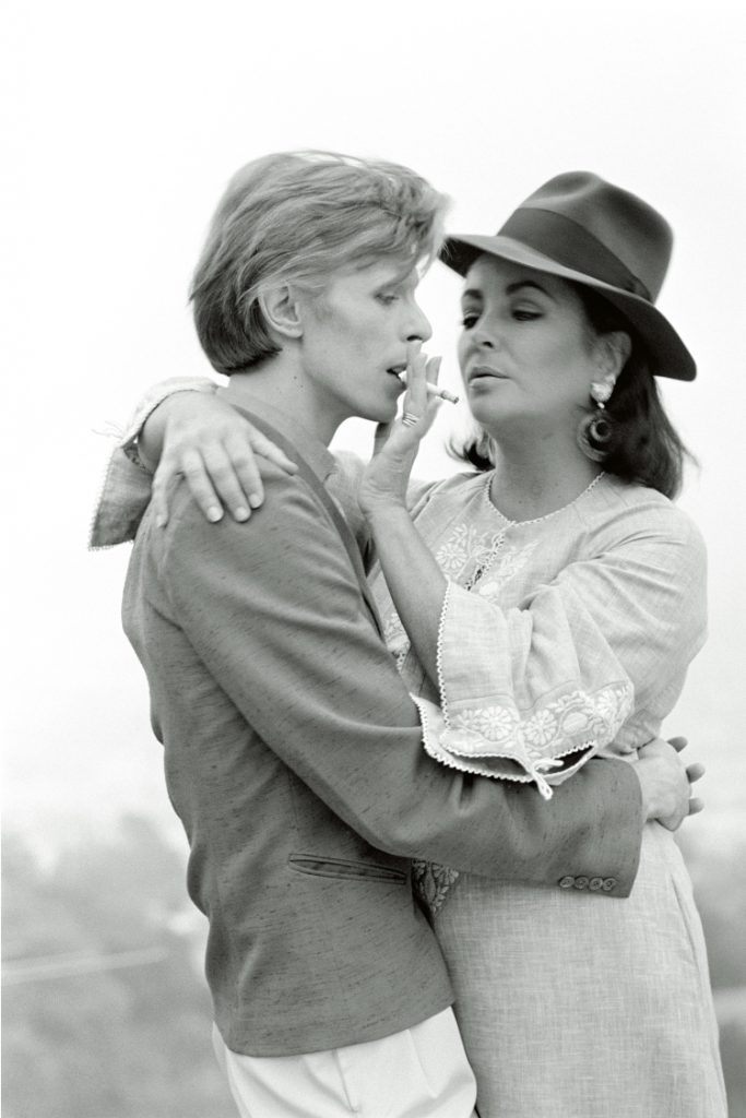 Singer David Bowie shares a cigarette with actress Elizabeth Taylor in Beverly Hills, 1975. It was the first occasion that the pair had met.