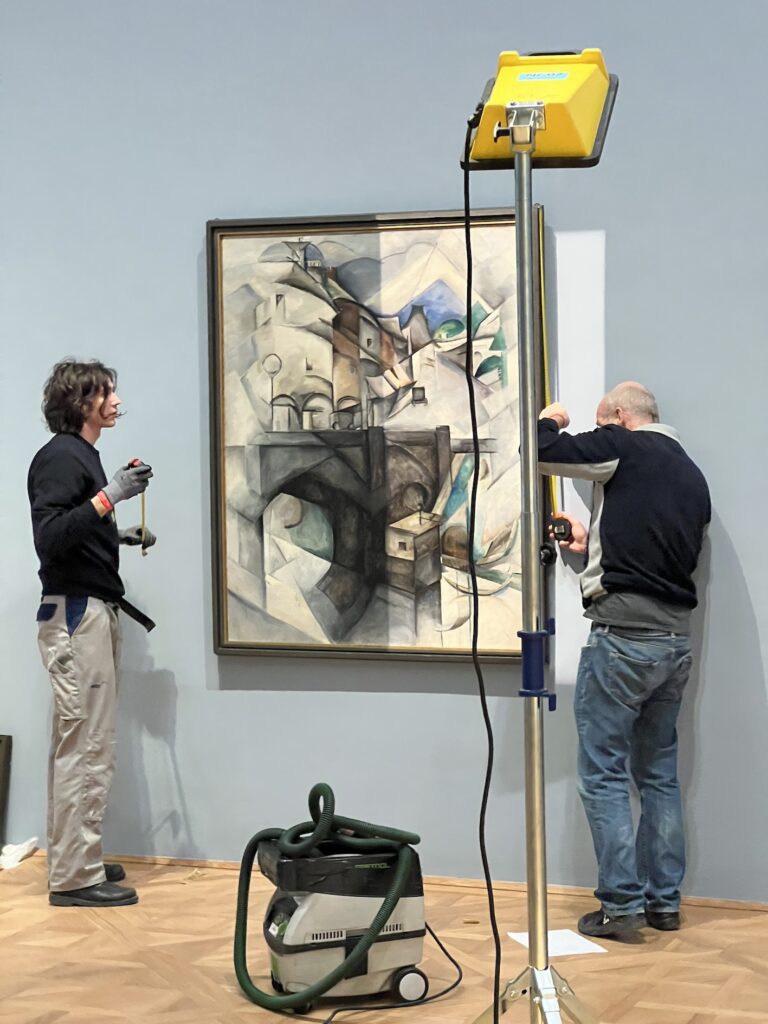 Curators installing an artwork from Ukraine featured in the exhibition In the Eye of the Storm, Vienna