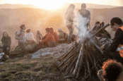 Image shows group of people at mountain campfire.