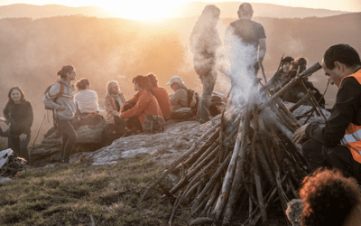 Image shows group of people at mountain campfire.