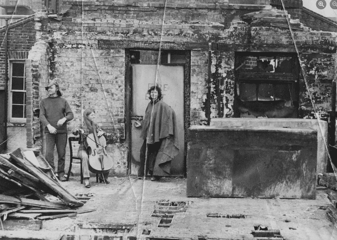 Image shows black and white photo of Ken and Mary Turner at Harmood Street with Kathy Geddes, cellist