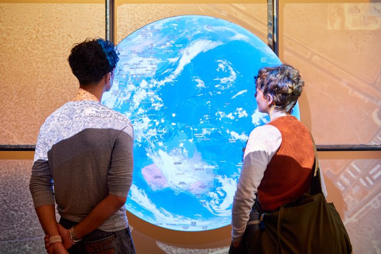 Visitors with Google Earth installation in Secret Maps exhibition at the British Library. Photography by Justine Trickett © The British Library Board